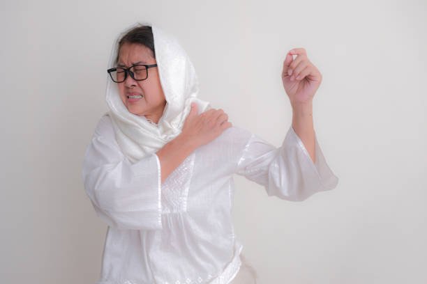Asian middle-aged woman pressing her left painful shoulder